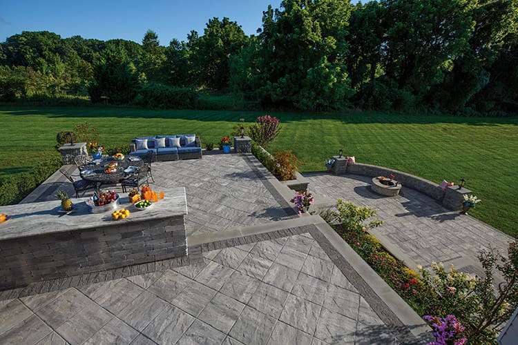 Custom outdoor living patio area with pavers and landscaped backyard design