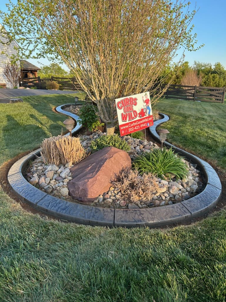Decorative concrete curbing installed around a landscaped flower bed in Potomac, MD featuring stamped edging and clean defined borders.